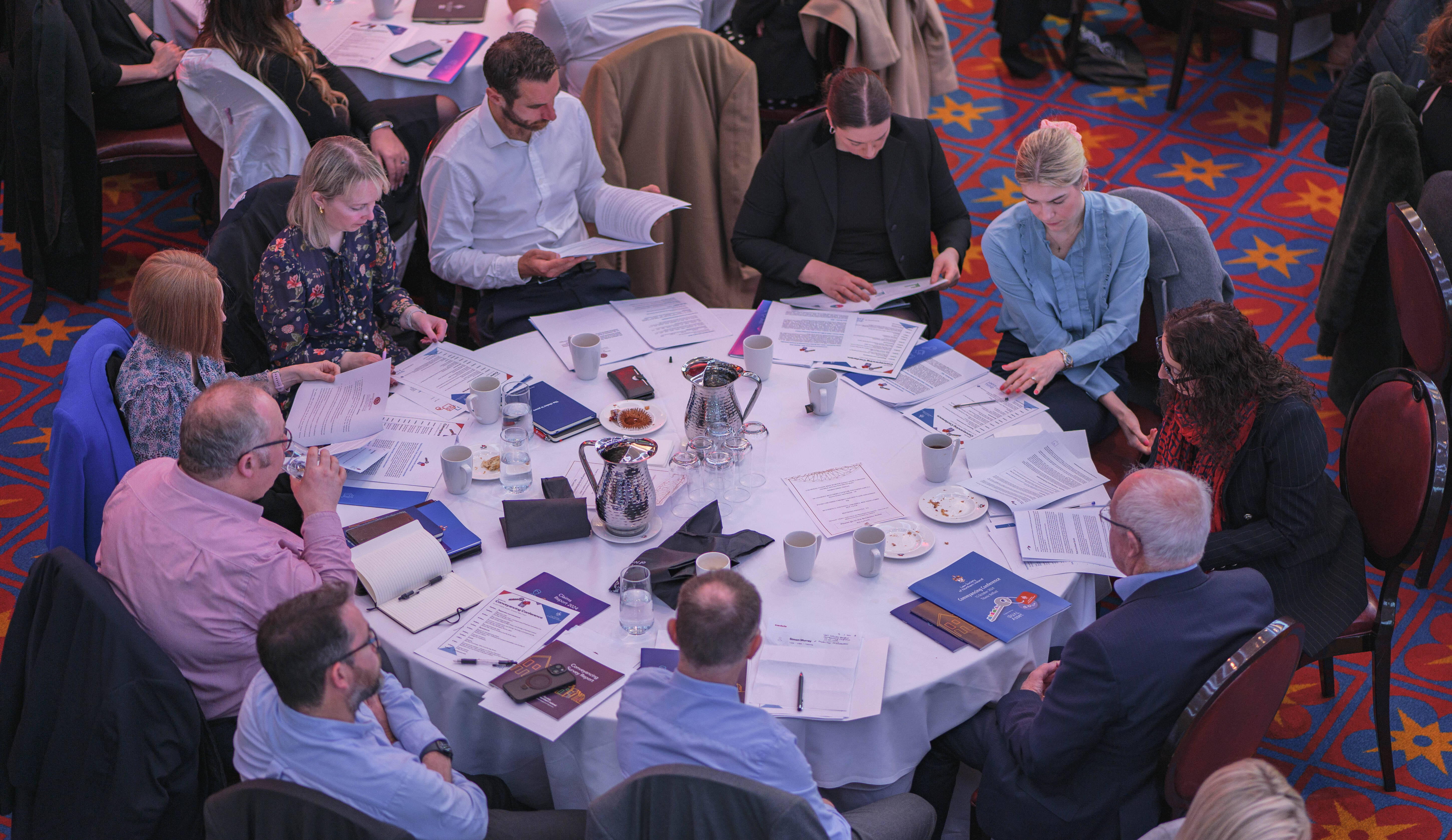 People sitting at a round table reading booklets