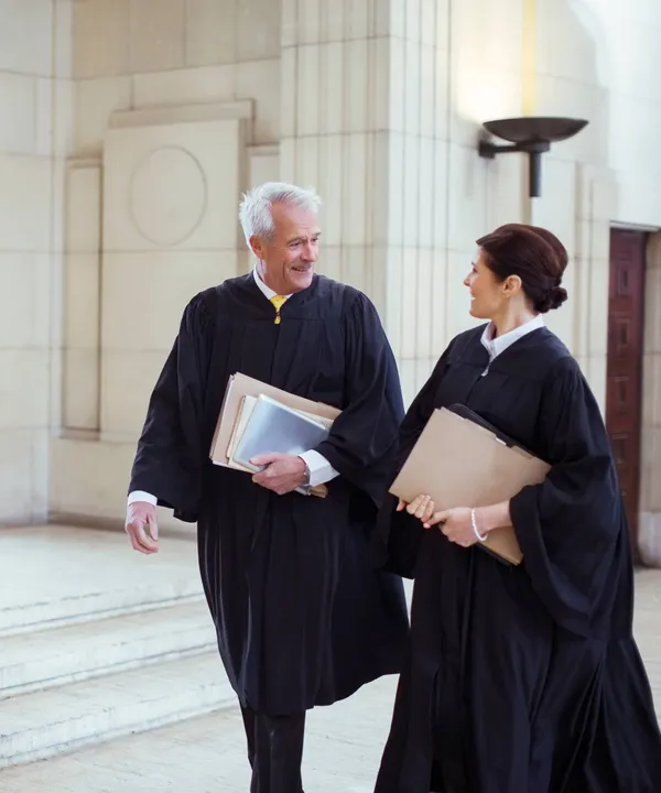 2 lawyers walking together and chatting while wearing robes